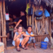 two girls sitting in the doorway of a traditional Mayan home